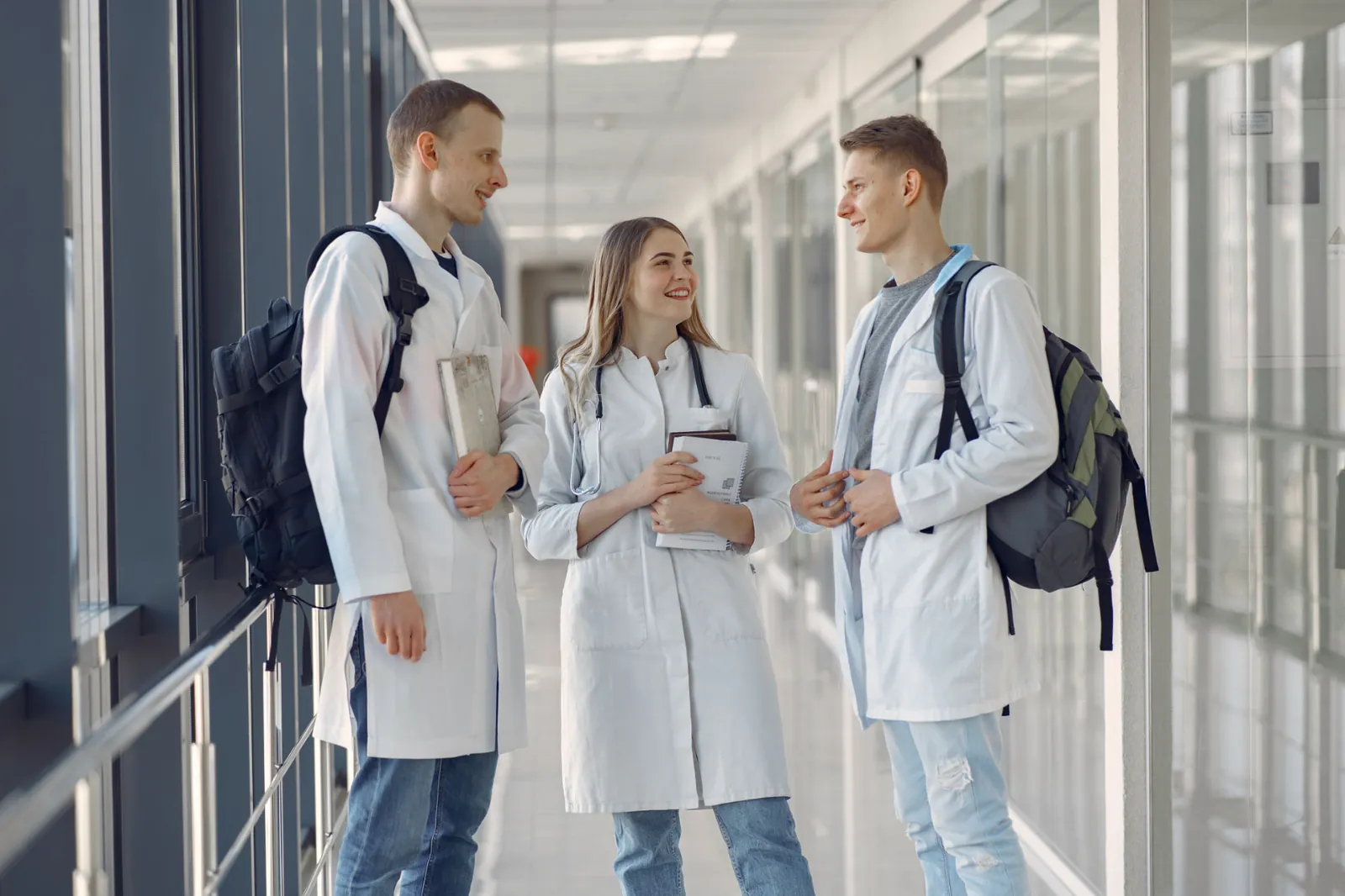 Medizinstudenten in weißen Kitteln im Gespräch auf einem Klinikflur